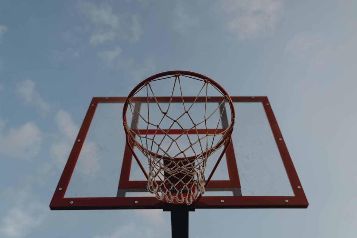 A basketball hoop with a clear backboard against a blue sky